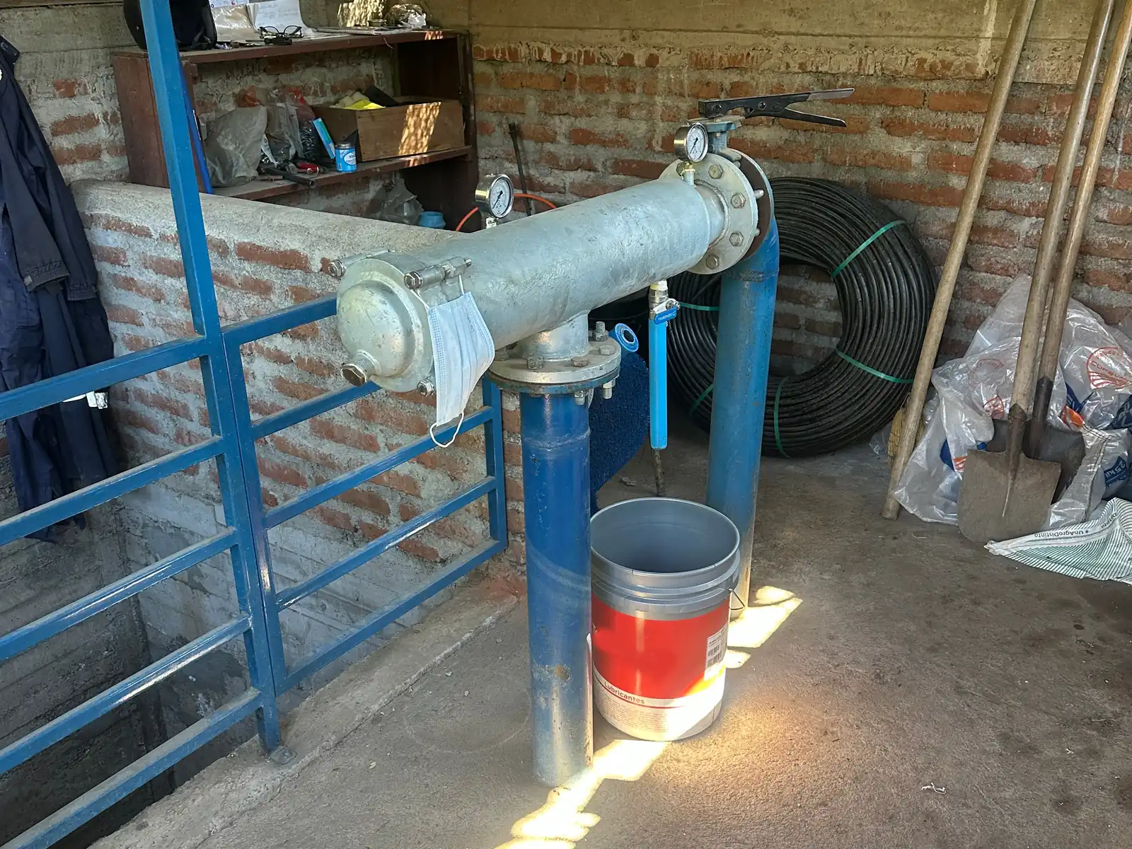 Caseta de bombeo con filtro horizontal, cañerías azules y suelo de concreto.